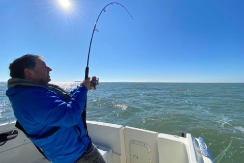 Competitor in sea angling competition using fishing rod