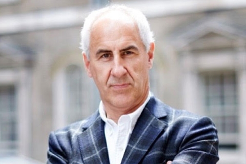 Headshot of Simon Ward looking to camera in suit with arms crossed