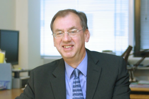 Stuart Iles sitting at desk and smiling at camera