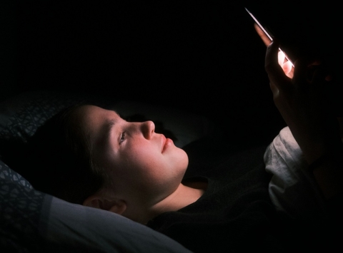 Young person in bed on their mobile phone