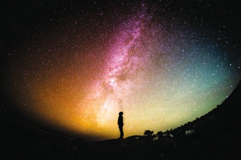 Image of a twilight sky with the silhouette of an individual in the foreground, standing in a field or park