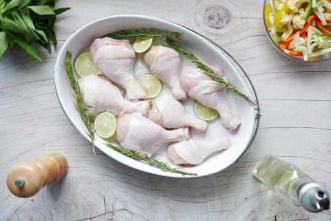 Raw chicken drumstick on in bowl on table