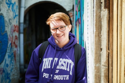 Student in purple hoodie standing in back alleys