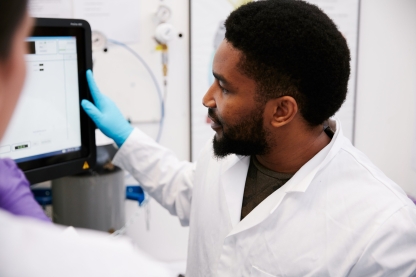 A male student in a lab coat wearing gloves