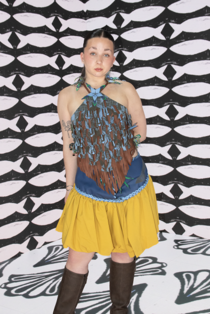 Student working a leather garment infront of black and white designed stage