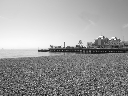 a photo of a pier by the beach in black and white