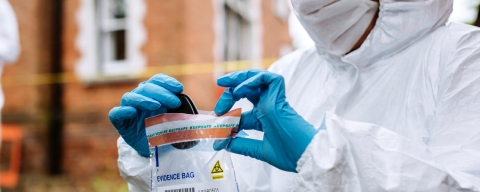 Forensic at crime scene handling keys into evidence bag