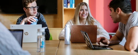 Students seated at a seminar with their laptops on a table