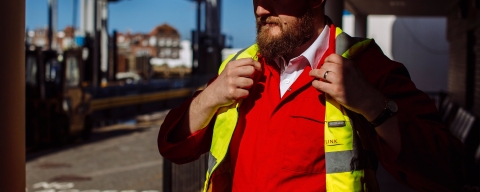 A man in hard hat adjusting his viz jacket