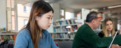 Female student with long hair in the library on a computer