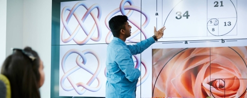 Student working on a board with mathematical equations