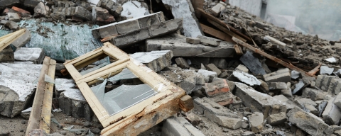 two people in high visibility suits searching through a pile of rubble and debri