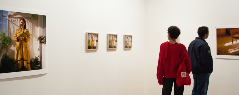 Two people looking at photographs on wall at exhibition