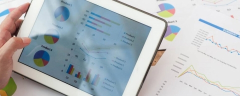 Data analytics student holds tablet with infographics