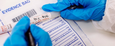 Forensic information technology student labelling an evidence bag wearing gloves
