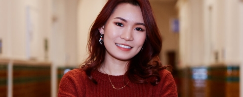 A woman with red hair and top, smiling