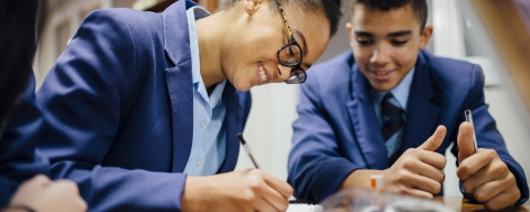 Two students smiling as they work together at a desk