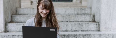 Person sitting on stone steps with a laptop.