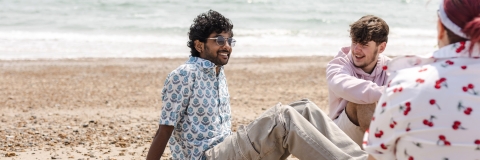 three students sat at the beach 