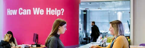 Female student standing at careers and employability help desk