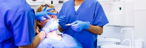 Two dental students work on patient