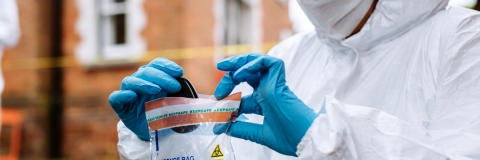 Forensic at crime scene handling keys into evidence bag