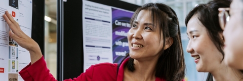 Photo of 2 attendees examining board.- Festival of Doctoral ResearchFOR GRADUATE SCHOOL USE ONLY