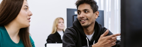Male student smiling and working on computer in facility