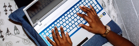 Student using laptop to complete university work in halls bedroom
