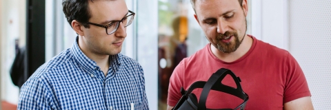 A staff member explaining to another staff member how a VR headset works