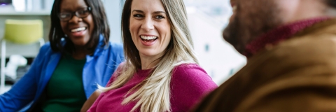 Three students smiling and chatting in learning space