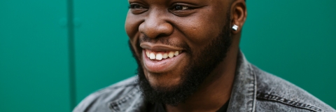 Smiling male student in front of a green wall