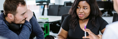 female in a research meeting taking notes with pen and paper