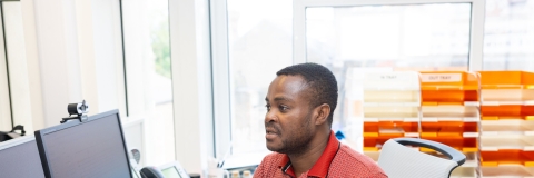 A man sat at a desk in front of a computer monitor.