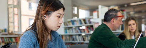 Female student with long hair in the library on a computer
