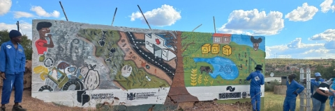 the completed bright mural in front of a bright blue sky 