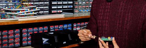 Male student in jumper working on a circuit board with a row of electrical components behind him