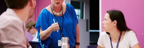 Meeting between large group in room with pink wall