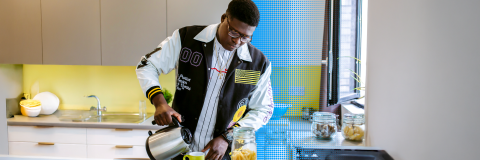 Student pouring tea in university student accommodation kitchen