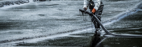 Man cleaning up oil spill on a beach in Thailand