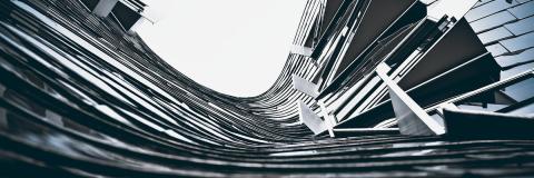 Ground angle view of a tall building with sinuous architecture, jutting windows and glossy exterior panels