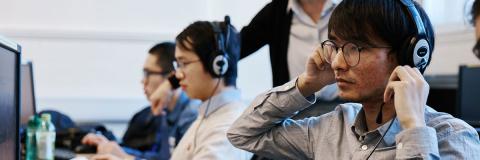 A student wearing headphones and looking at a computer screen.