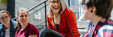 Students sitting on steps outside and laughing