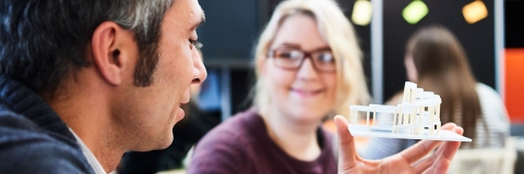 A man holding a model structure and smiling