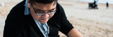 A student studying at the beach.