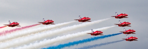 Red aeroplanes leaving smoke trails