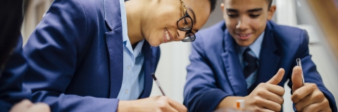 Two students smiling as they work together at a desk