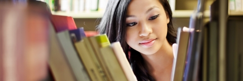 Woman looking through bookshelf 