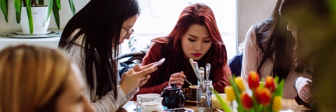 A group of students at a restaurant table eating and socialising