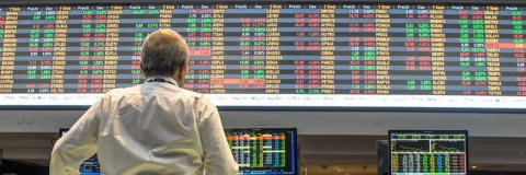 Person standing in front of screens showing financial data